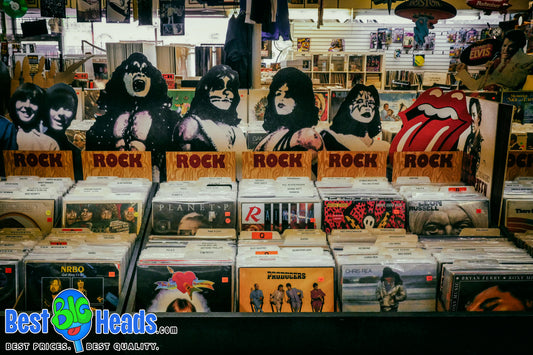 Vintage 1970s rock 'n' roll cardboard cutouts of iconic band members displayed above vinyl records in a nostalgic record store.