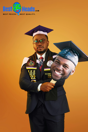 A newly graduated student in a cap and gown proudly holding a large face cutout of himself, celebrating his achievements and the milestone he has unlocked with a beaming smile.