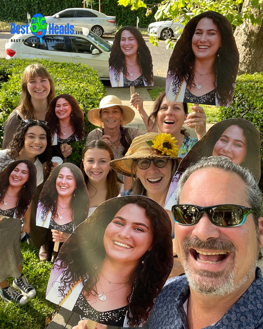 A proud and supportive family cheering enthusiastically while holding face cutouts of their newly graduated daughter, celebrating her achievement together.