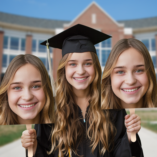A newly graduated student proudly holding a large cutout of her own face before the graduation ceremony, smiling with excitement.