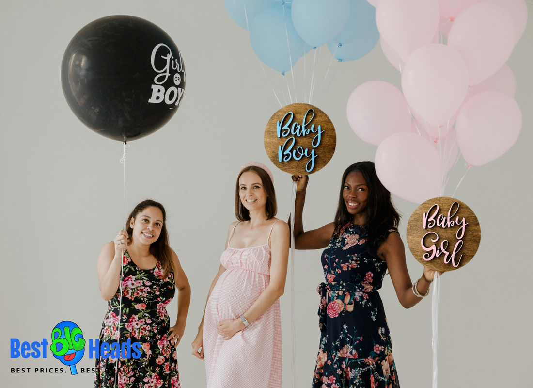 Group of friends smiling and cheering while celebrating a baby gender reveal, with balloons and decorations in the background.