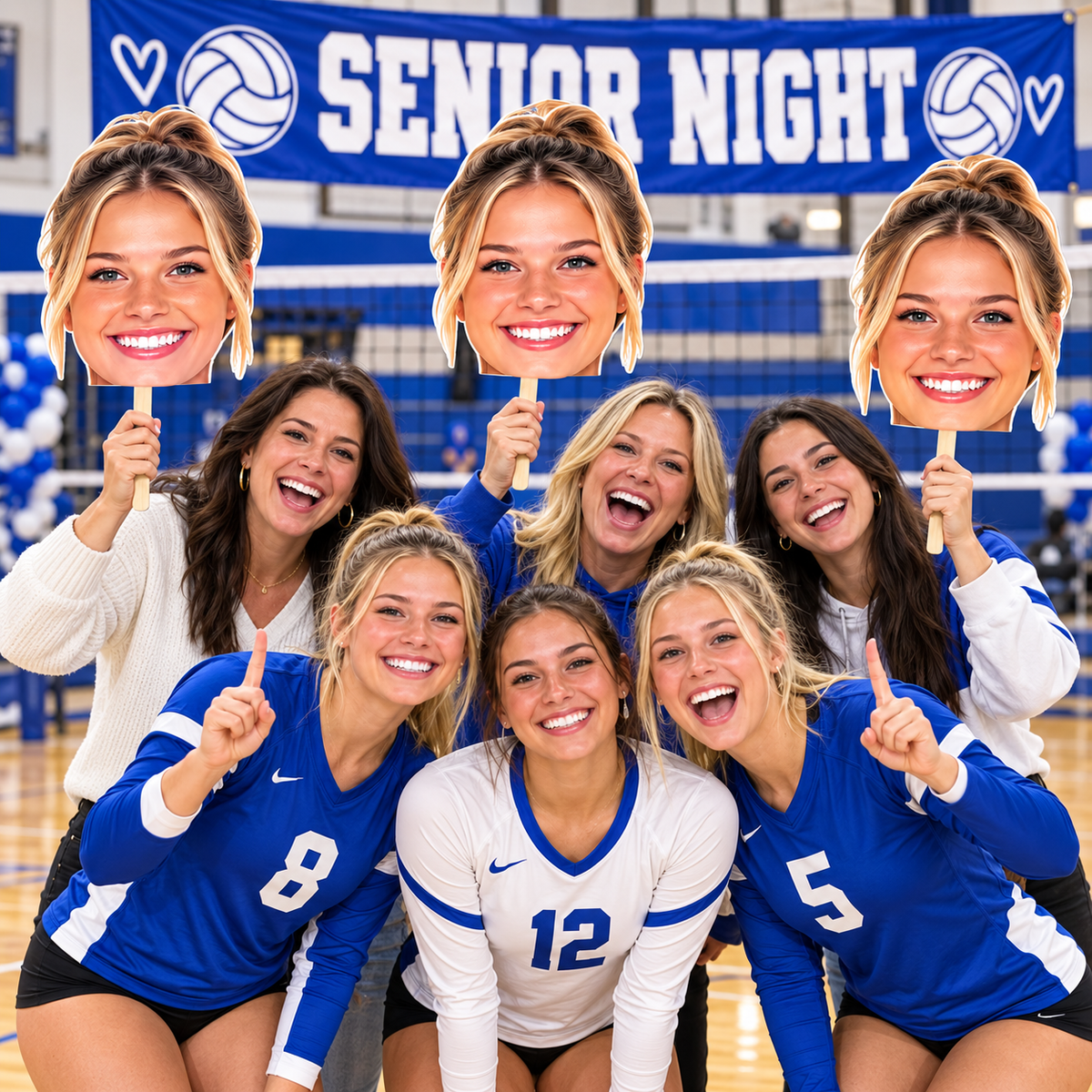 Volleyball players and fans posing courtside with oversized custom face cutouts for Senior Night